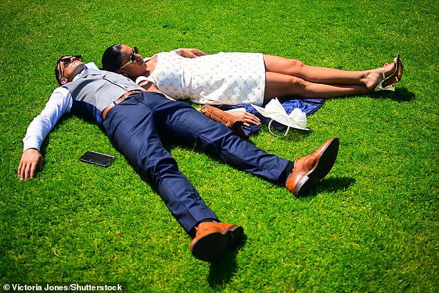 Making the most of the sunshine! Racegoers sunbathe on the grass at Ascot racecourse