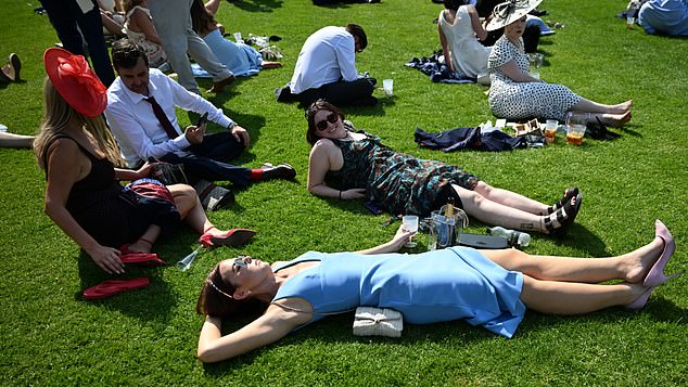 Relaxing in the sunshine! Ladies lie down on the grass to catch a tan during Royal Ascot