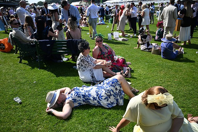 Revellers take a break from the action to sunbathe and sit down in the hot temperatures