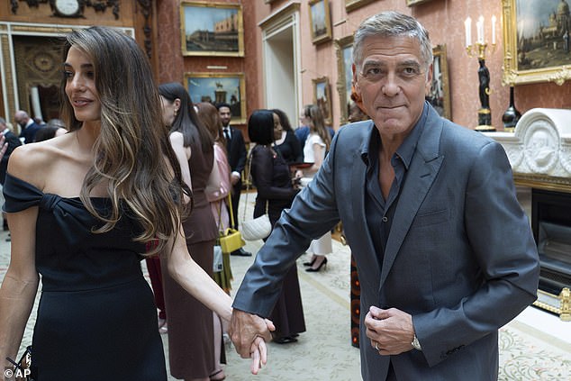 Giving her a hand! George Clooney sweetly takes his glamorous wife Amal's hand at today's reception