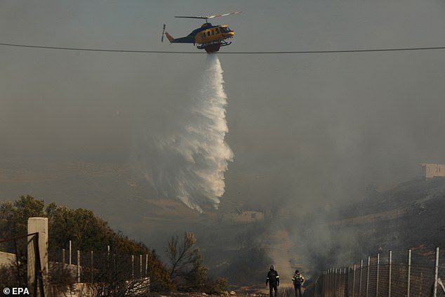 GREECE: A firefighting helicopter douses a wildfire burning in the coastal region of Palaia Fokaia on Thursday