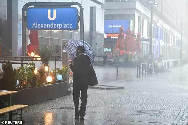 GERMANY: A man shields himself with an umbrella on Alexanderplatz square during stormy weather in Berlin