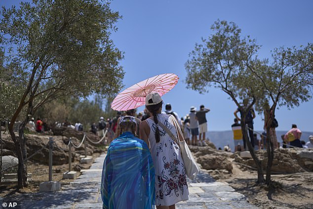 GREECE: Tourists with an umbrella walk at the foot Acropolis Hill, Thursday, June 26