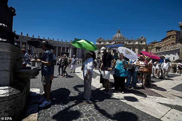 VATICAN CITY -- People shielding under umbrellas queue to fill their water bottles from a fountain