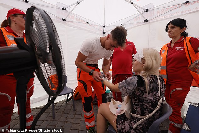 ROME -- A woman is tended to during to sweltering heat at a Red Cross emergency point