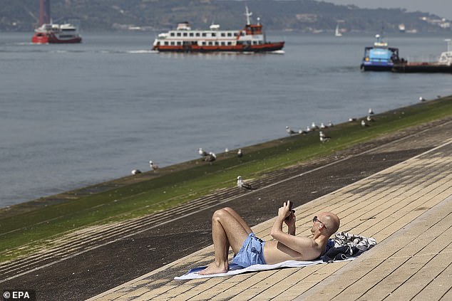 PORTUGAL -- A man sunbathes near the Tagus River in Lisbon as a heat bomb hits Europe