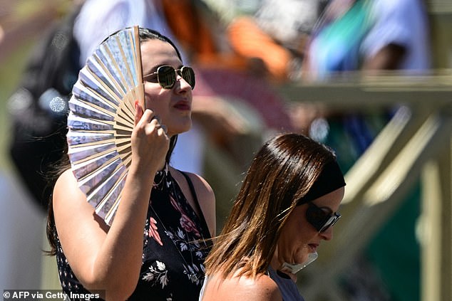 VATICAN CITY -- A woman uses a fan to cool herself during the heat as Pope Leo XIV addesses the crowd