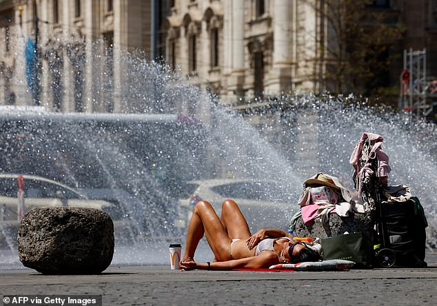 GERMANY -- A woman bathes in the sun next to a fountain at Munich's Karlsplatz square