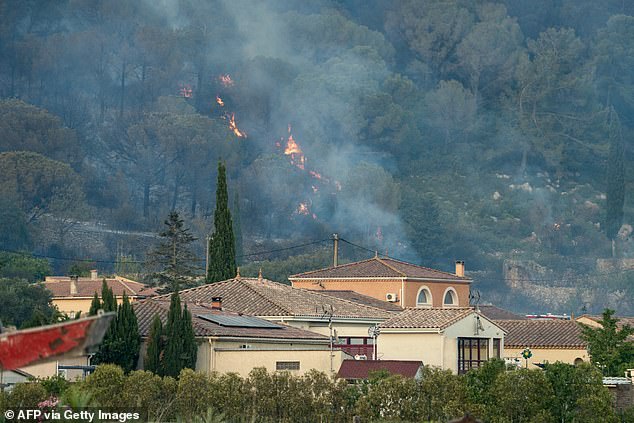 A wildfire blazes near to houses in Bizanet, southwest France