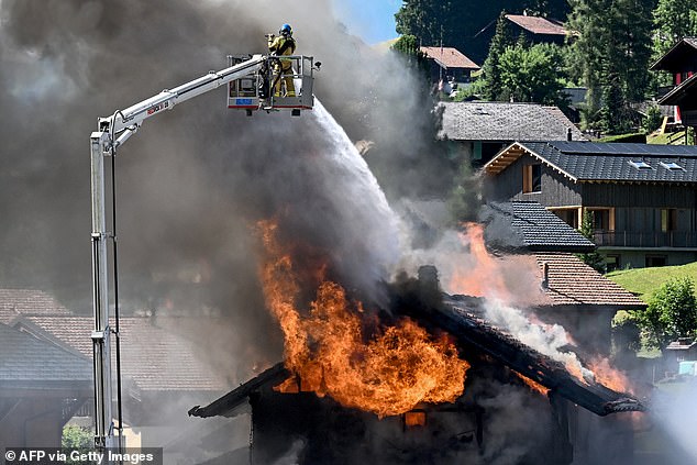 Firemen tackle a blaze at a chalet in the centre of the resort of Morgins, western Switzerland next to the French border