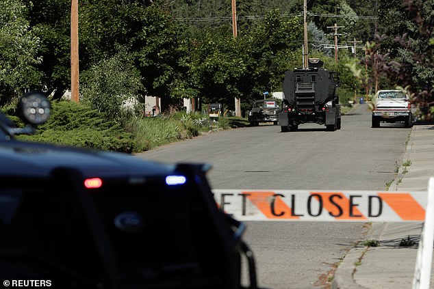 An armored police vehicle travels towards Canfield Mountain