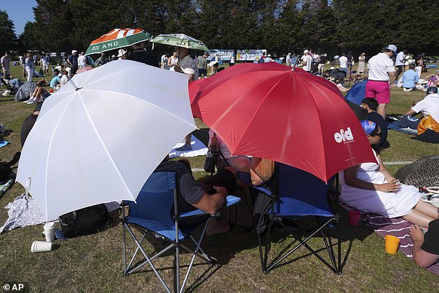 A few people try and find shelter from the heat under umbrellas