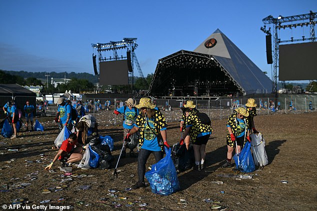 Litter pickers collect rubbish from the field of the Pyramid Stage at the end of the Glastonbury