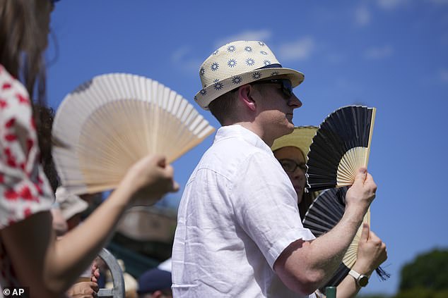 Visitors use a fan to stay cool at the Wimbledon Tennis Championships in London