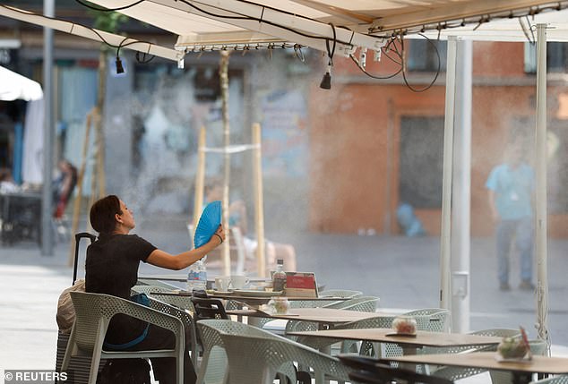 A woman uses a hand fan to cool off during the first summer heatwave in Seville, Spain