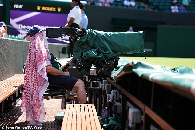 A TV camera operator shelters from the sun