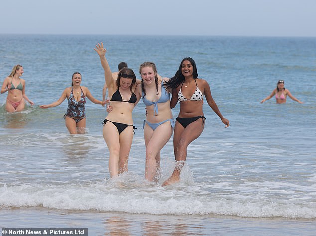 Three girls swim in the sea in Tynemouth
