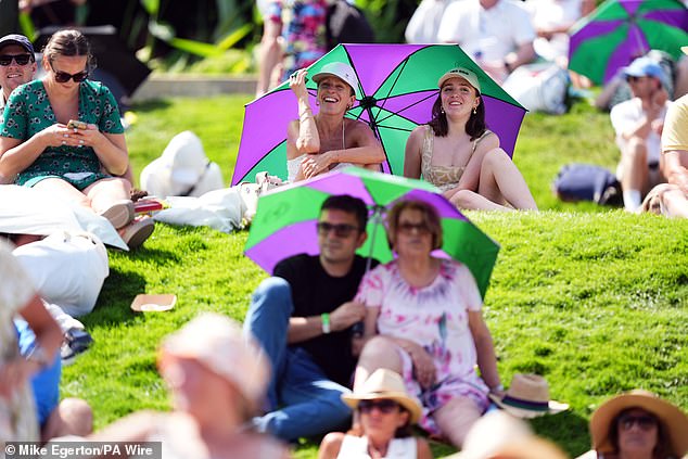 Watchers protect themselves from the sun with umbrellas