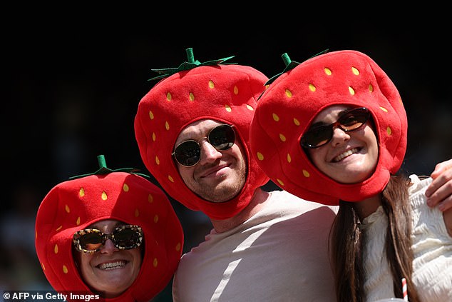 Spectators wearing strawberry masks pose on the first day of the 2025 Wimbledon Championships