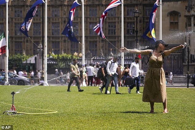 A woman stands in a sprinkler in Parliament Square, in London