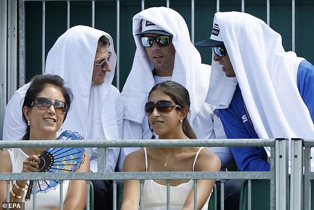 Spectators use wet towels to cool down at the Wimbledon Championships