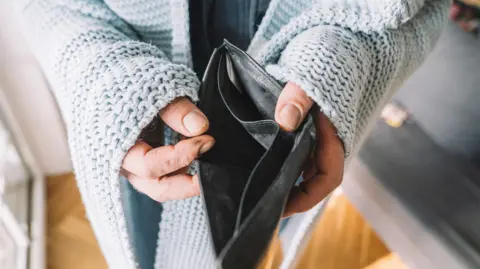 Getty Images Hands of man wrapped in blanket holding empty wallet 