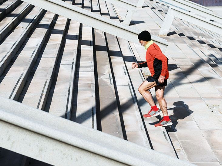 An older adult runs up stairs outside in running gear