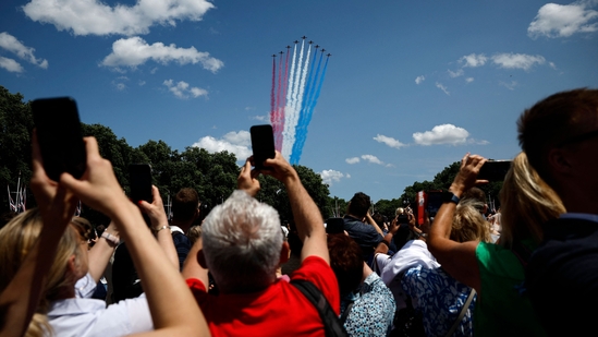 Members of the public watch as the British Royal Air Force's (RAF) aerobatic team, the "Red Arrows", perform a flypast over Buckingham Palace during the King's Birthday Parade "Trooping the Colour" in London on June 14, 2025. The ceremony of Trooping the Colour is believed to have first been performed during the reign of King Charles II. Since 1748, the Trooping of the Colour has marked the official birthday of the British Sovereign. Over 1500 parading soldiers and almost 300 horses take part in the event. (Photo by BENJAMIN CREMEL / AFP)(AFP)
