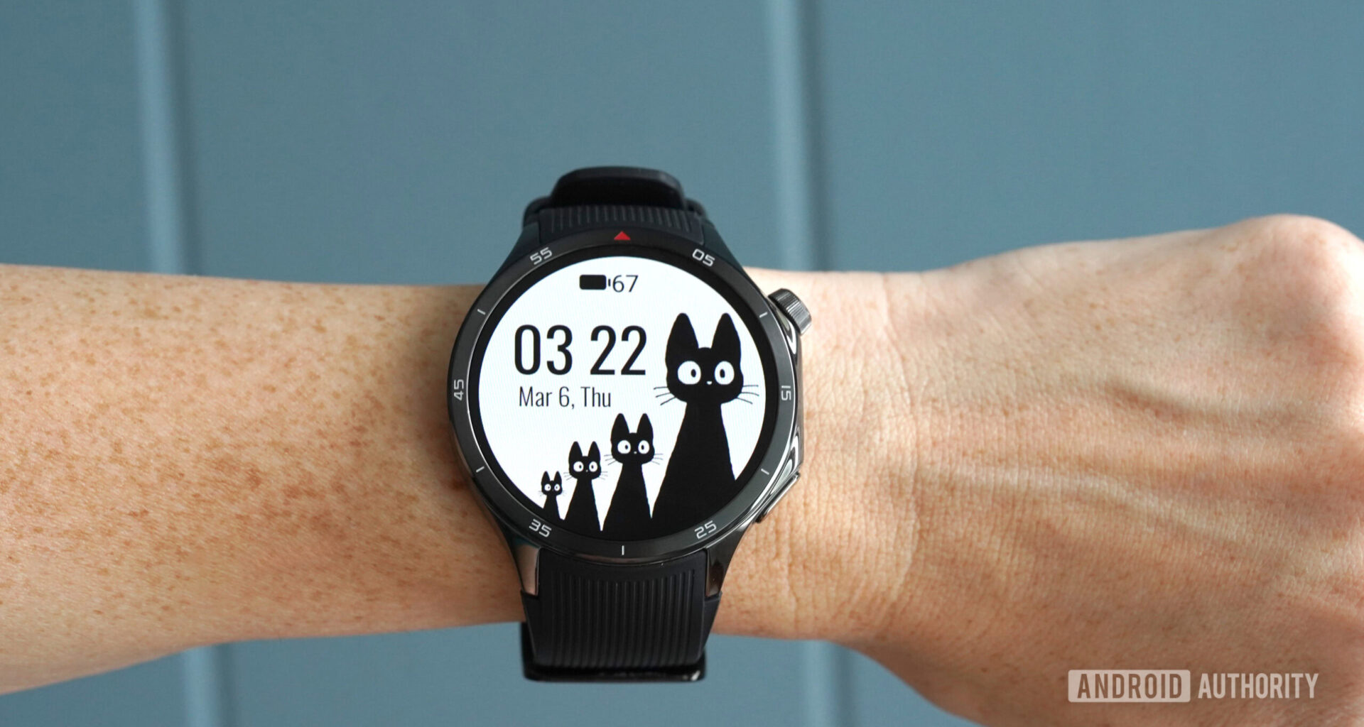 A OnePlus Watch 3 displays the Black Cats WearOS watch face.