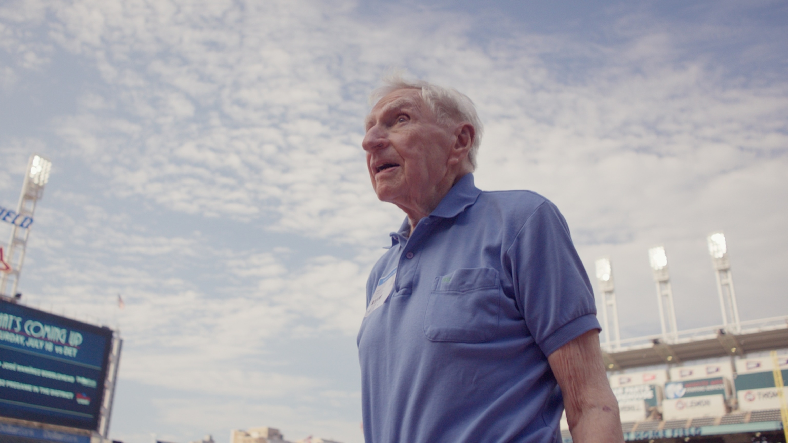 Dr Tucker wearing a blue polo shirt as he stands in a stadium