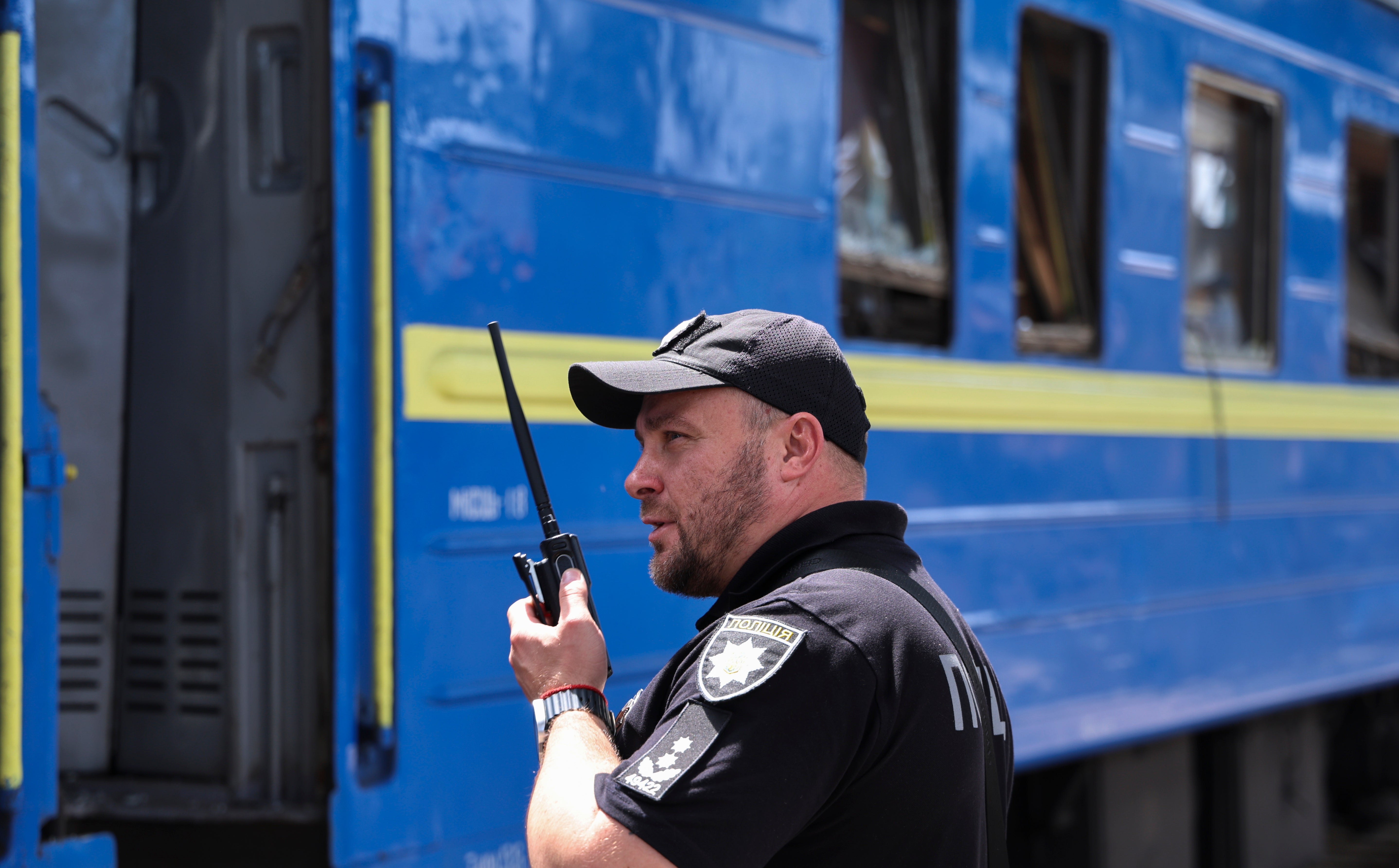 A policeman speaks by radio near a damaged passenger train following massive Russian shelling in the city of Dnipro