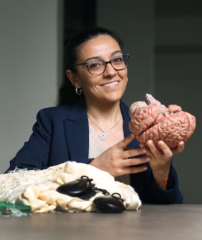 Ana Belén López holds a reproduction of a human brain next to a shawl and some castanets.