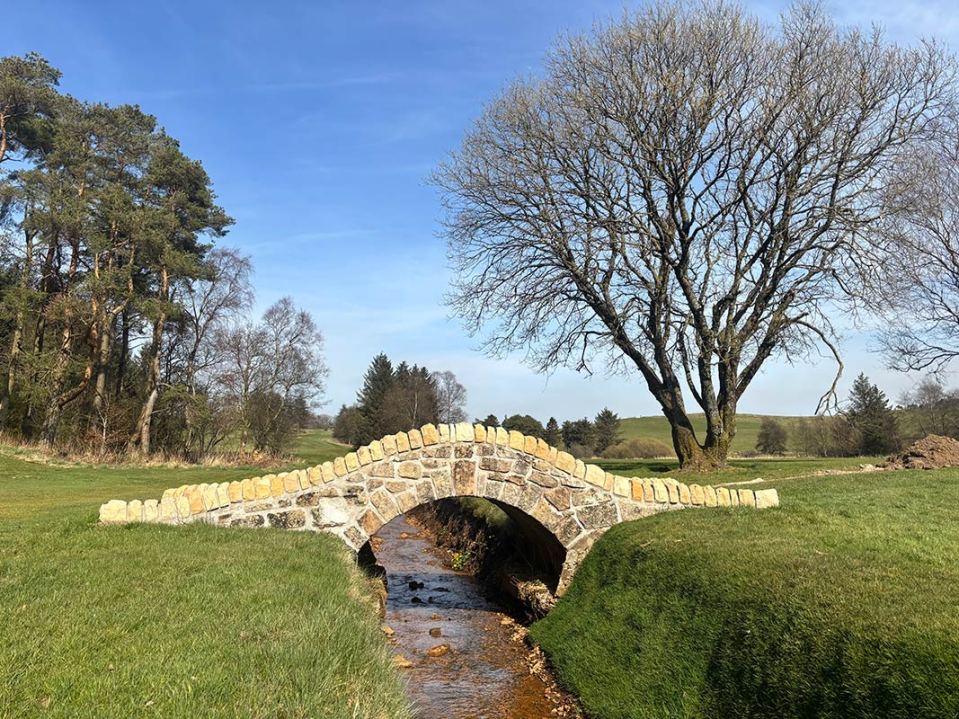 Stone bridge over a stream on a golf course.