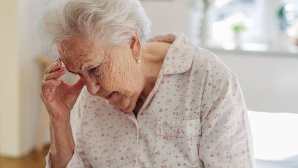 Elderly woman holding her head