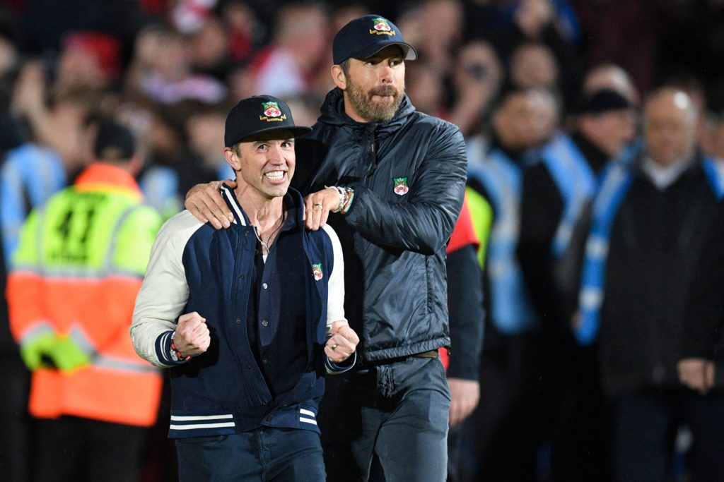 Rob McElhenney and Ryan Reynolds celebrate on the pitch after the English National League football match between Wrexham and Boreham Wood