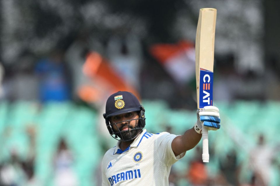 India's captain Rohit Sharma raises his bat after scoring a century (100 runs) during the first day of the third Test cricket match between India and England at Niranjan Shah stadium in Rajkot on February 15, 2024. (Photo by Punit PARANJPE / AFP) / -- IMAGE RESTRICTED TO EDITORIAL USE - STRICTLY NO COMMERCIAL USE -- (Photo by PUNIT PARANJPE/AFP via Getty Images)