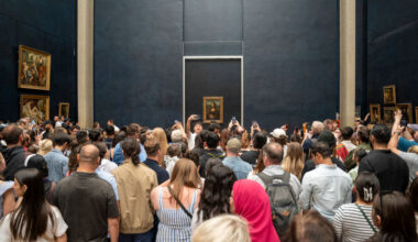 A crowd of people before a painting.