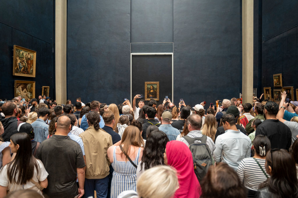 A crowd of people before a painting.