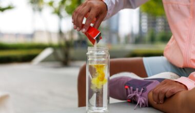 young woman in running gear pouring electrolyte powder into a clear bottle filled with water.