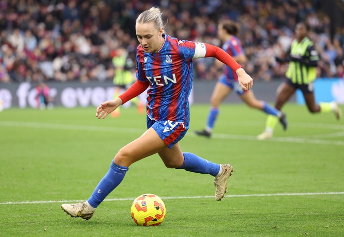 Josie Green pictured playing football, with a yellow and red ball in between her legs.