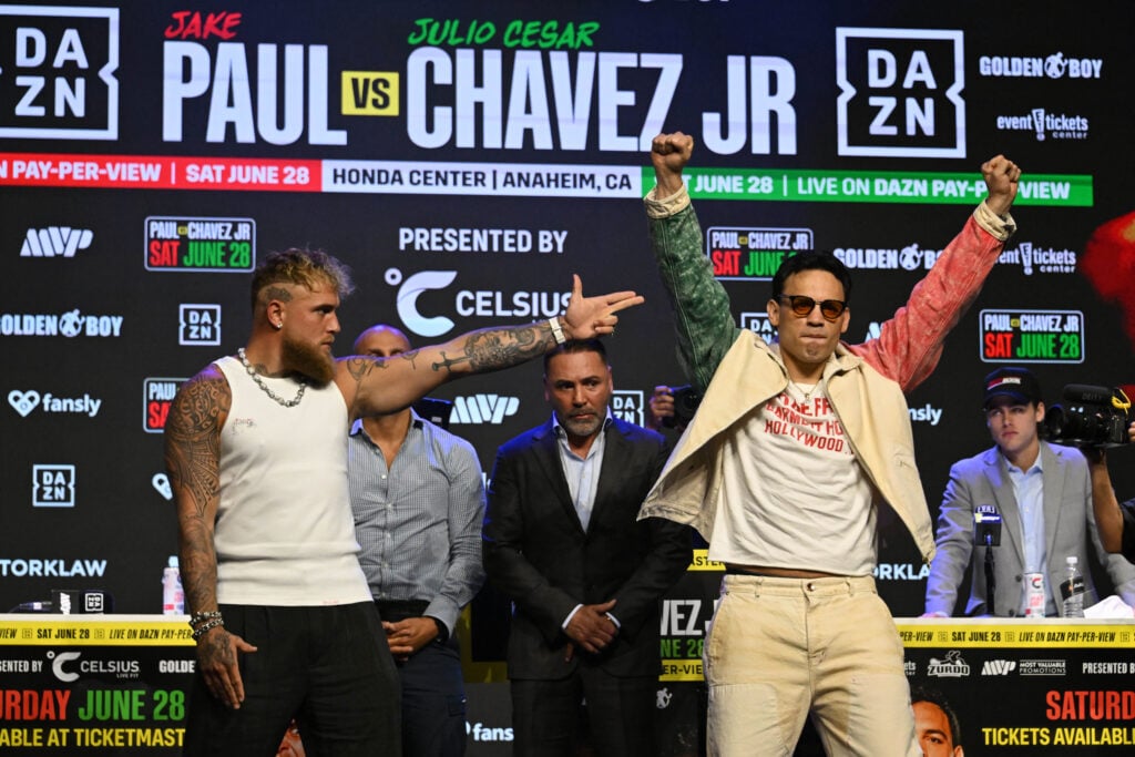 Jake Paul points a gun signal at Julio Cesar Chavez Jr who holds his arms aloft