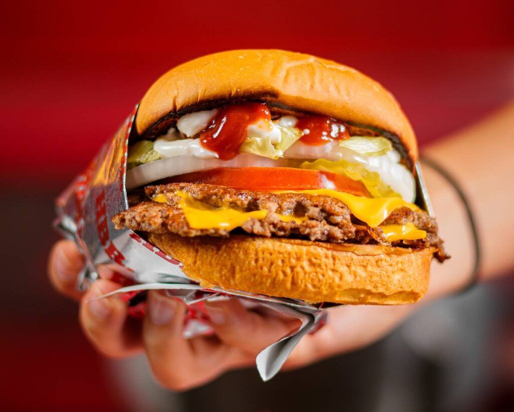 Person holding a HBR smash burger close to the camera