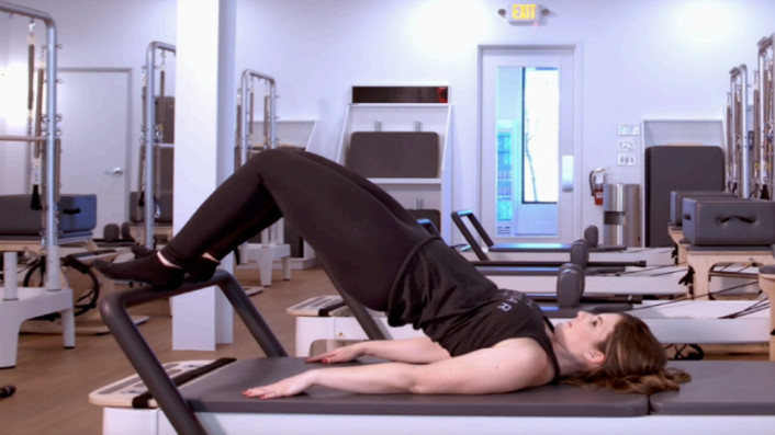 Woman on a Reformer Pilates machine demonstrating an exercise