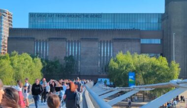 Crowds of people crossing a bridge walking towards the Tate Modern