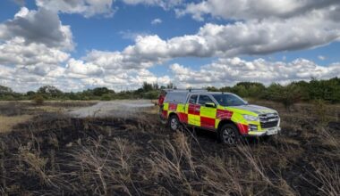 Fire vehicle parked on burnt heathland.
