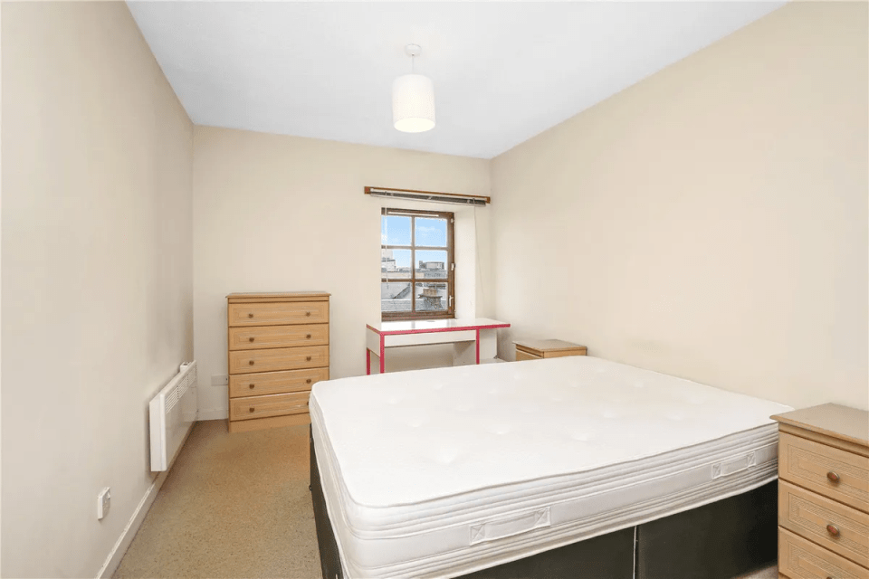 Bedroom with double bed, desk, and chest of drawers.