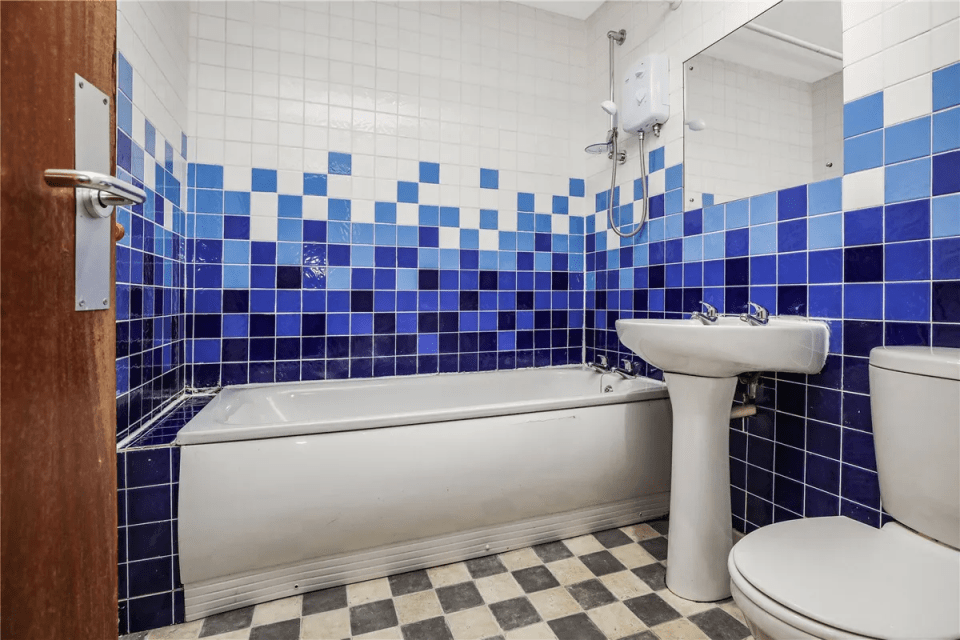 Bathroom with blue and white tiled walls, bathtub, sink, and toilet.
