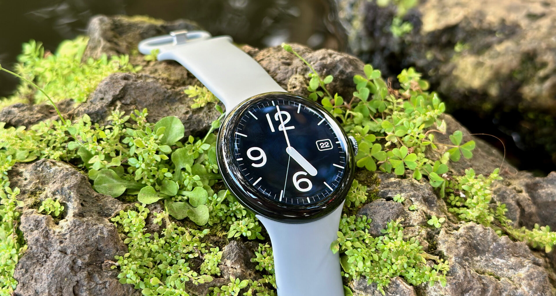 The Google Pixel Watch 3 sitting on a rock with the Pilot Bold watch face