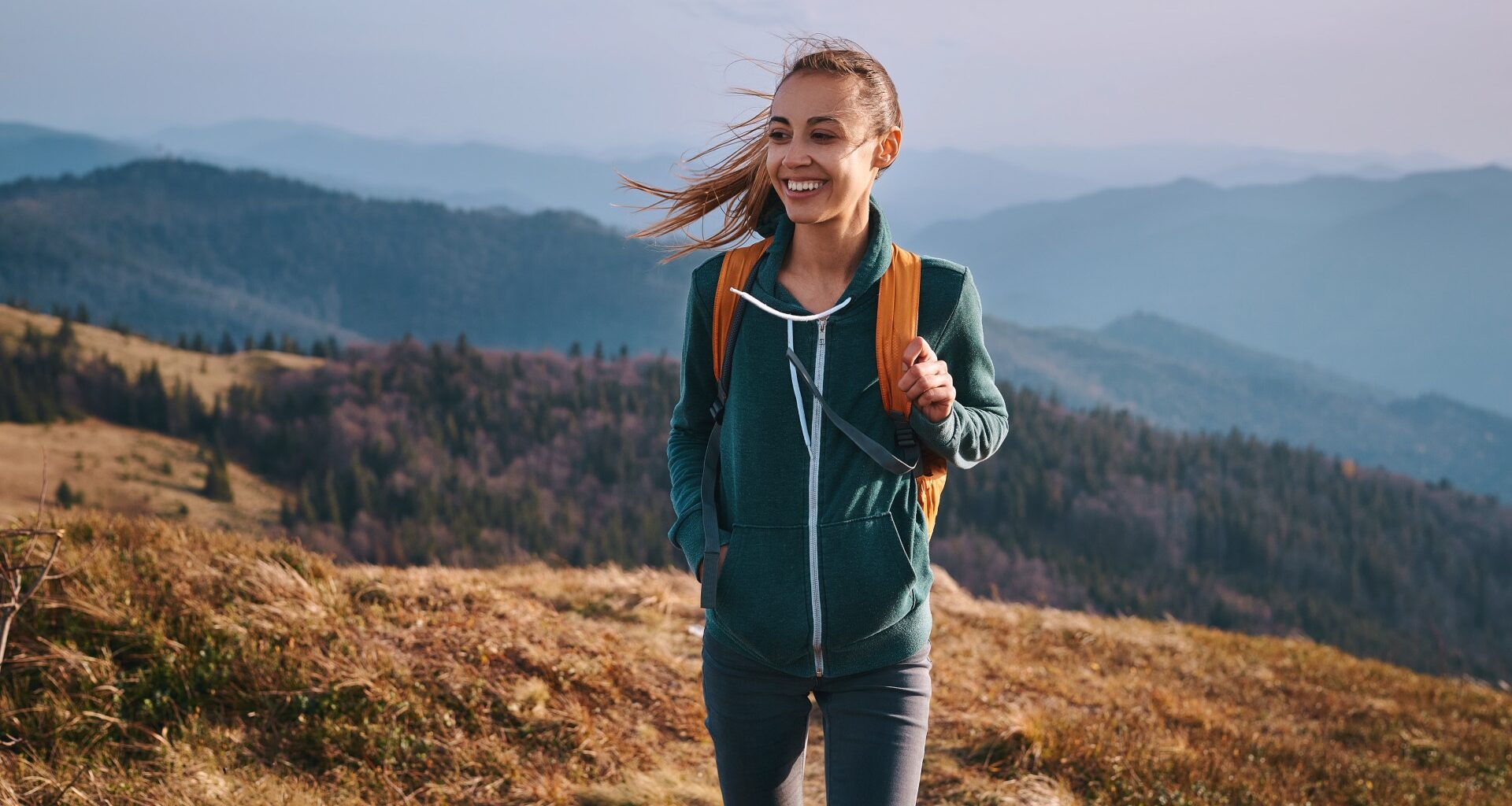 Woman outdoors in nature walking with a backpack on smiling
