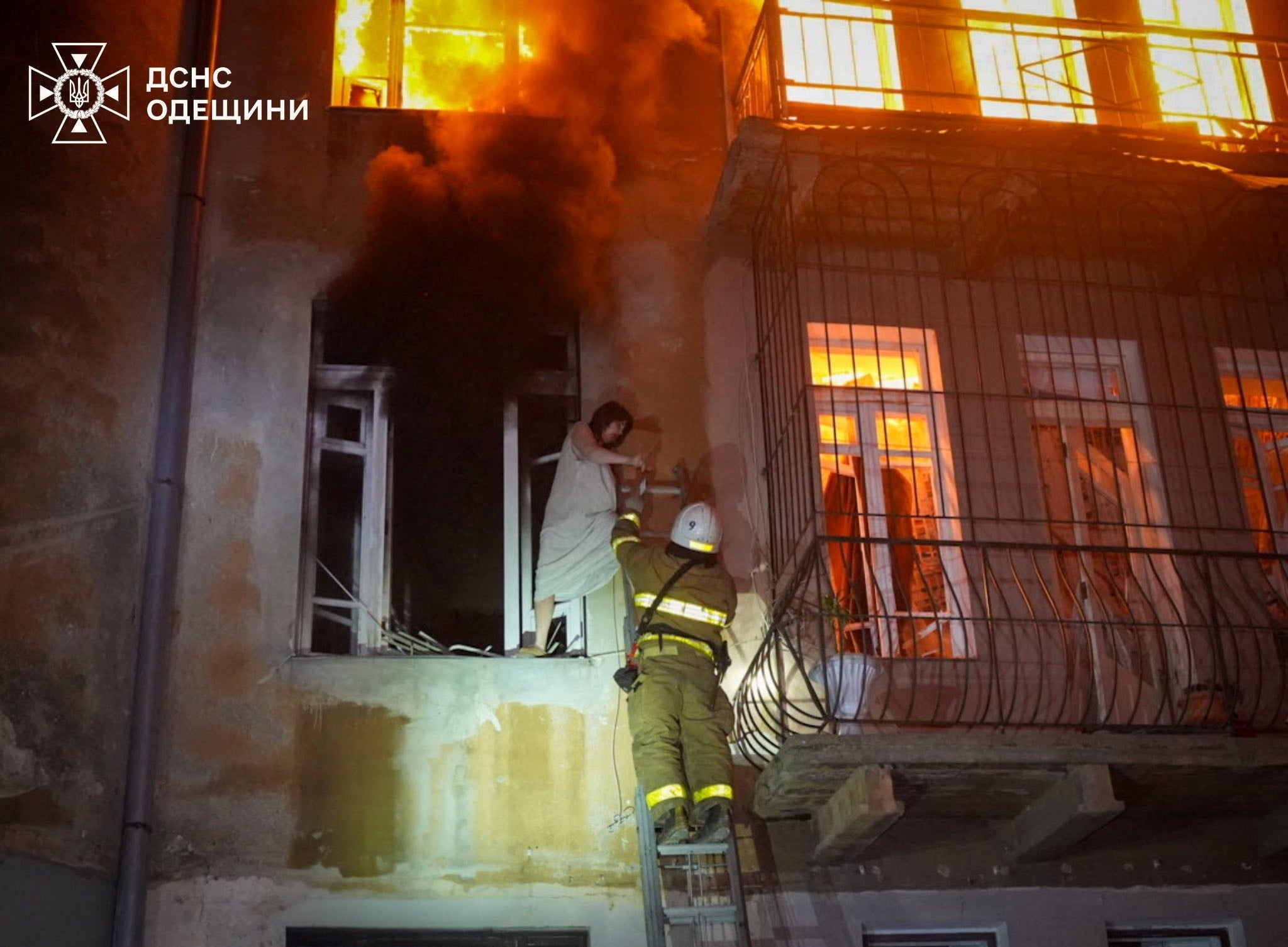 A firefighter helps a woman during an evacuation from her apartment building hit by a Russian drone strike in Odesa, Ukraine